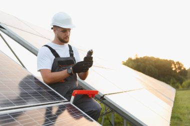 Bir alana güneş panelleri kuran mühendis, el aletleri ile temiz ve sürdürülebilir enerji çözümleri sağlıyor