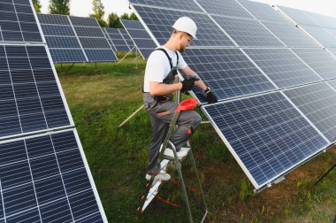 Dışarıda güneş panelleri kuran, sürdürülebilir elektrik üretimi ve yeşil teknolojiye katkıda bulunan güvenlik ekipmanları işçisi