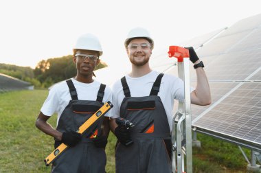 Mühendisler fotovoltaik paneller kuruyor, sürdürülebilir enerji sağlıyor. Yenilenebilir enerji üretimi için takım çalışması