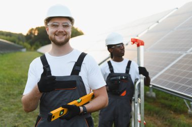 Güneşli bir alana güneş panelleri kuran mühendisler, takım çalışması ve yenilik yoluyla yenilenebilir ve sürdürülebilir enerji üretiyorlar.
