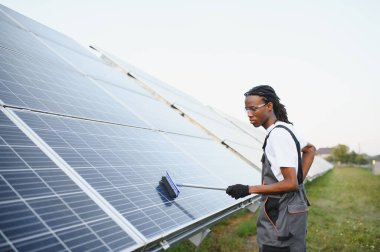 İnsan teknisyeni güneş panellerini cam sileceğiyle temizliyor, sürdürülebilir ve yenilenebilir enerji üretimi için bakım yapıyor.