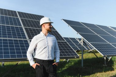 Büyük bir güneş enerjisi santralinde duran, yenilenebilir enerji teknolojisini yöneten bir mühendis.