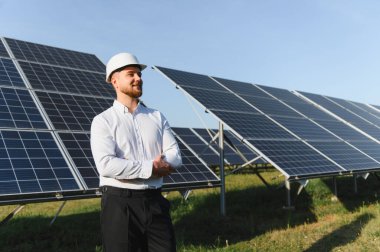 Güneş panellerini izleyen mühendis yenilenebilir enerji, yeşil teknoloji ve sürdürülebilir geleceği temsil ediyor.