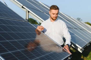 Yenilenebilir enerji güneş paneli kurulumunu kontrol eden genç adam, yeşil enerji üretimi için sürdürülebilirlik sağlıyor