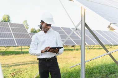 Akıllı yönetim için tablet kullanan ve güneş paneli kurulumunu denetleyen Afrika kökenli Amerikalı mühendis.
