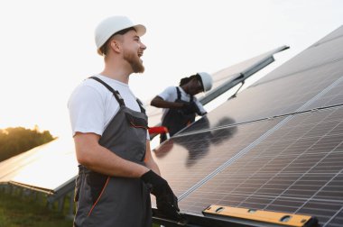 Fotovoltaik panelleri tamir etmeye çalışan adamlar. Sürdürülebilir elektrik üretimi için güneş enerjisi kullanılıyor