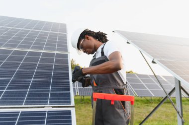 Afrikalı Amerikalı teknisyen bir enerji santraline yeni güneş enerjisi panelleri kuruyor, sürdürülebilir bir alanda temiz elektrik üretiyor.