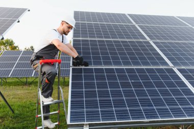 Genç teknisyen yeşil enerji çiftliğine yeni güneş panelleri kuruyor. Temiz elektrik üretimi ve sürdürülebilir gücü teşvik etmek