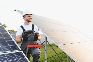 Mutlu işçi fotovoltaik paneller kuruyor, başparmağını gösteriyor. Yenilenebilir enerji ve yeşil teknoloji kavramı