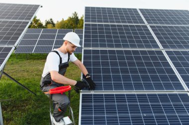 Teknisyen güneş panellerini açık hava sırasına yerleştiriyor, sürdürülebilir, temiz fotovoltaik gücü güvenlik ekipmanları ve aletleriyle geliştiriyor.