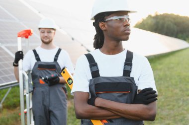 Çeşitli mühendisler güneş panelleri kuruyor, sürdürülebilir gelecek için temiz enerji üretiyorlar. Bir güneş enerjisi santralinde ekip çalışması