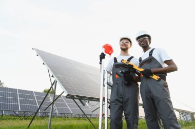 İki farklı mühendis güneş panelleri kuruyor, sürdürülebilir enerji üretimi için takım çalışması yapıyorlar.