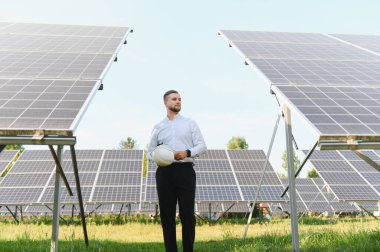 Büyük bir güneş enerjisi santralinde duran genç mühendis, yenilenebilir enerji teknolojisine bakıyor.