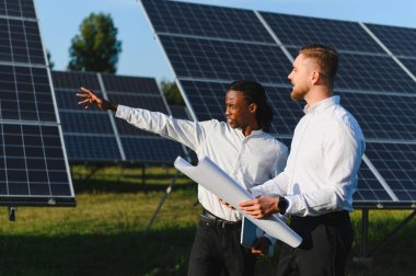 İki farklı mühendis güneş paneli alanında yenilenebilir enerji ve temiz enerji üzerine planlar ve yenilikler tartışıyorlar.