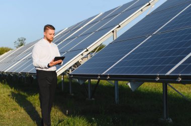 Dijital tablet kullanarak güneş paneli performansını izleyen mühendis yenilenebilir enerji üretimi ve sürdürülebilirliği sağlıyor