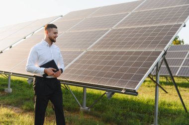 Güneş panellerini denetleyen mühendis çevresel sürdürülebilirlik için yenilenebilir enerji üretimini yönetiyor.