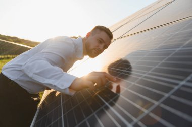 Güneş paneli alanını inceleyen erkek mühendis, altın saat boyunca yeşil enerji teknolojisinin verimliliğini ve sürdürülebilirliğini sağlıyor