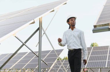 Afrika kökenli Amerikalı mühendis, yenilenebilir enerji çiftliğinde yürür ve güneş panellerini izler.