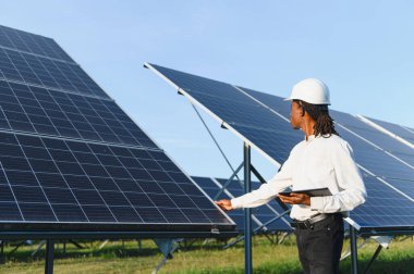 Büyük bir güneş çiftliğindeki güneş enerjisi panellerini inceleyen erkek mühendis, sürdürülebilir enerji üretimi ve yenilenebilir enerji