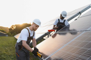 İki işçi güneş çiftliğine fotovoltaik paneller kurarak temiz ve sürdürülebilir elektrik enerjisi üretiyor.