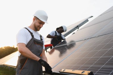 Mühendisler güneş panellerini yerleştiriyor, temiz ve yenilenebilir enerji için sürdürülebilir bir enerji santrali inşa ediyorlar.