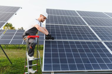 Bir alana güneş panelleri kuran mühendis, yeşil gelecek için temiz teknolojiyle sürdürülebilir elektrik enerjisi üretiyor