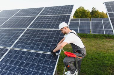 Güneş panelleri üzerinde çalışan erkek mühendis, sürdürülebilir enerji üretimi için yenilenebilir enerji sistemi kuruyor
