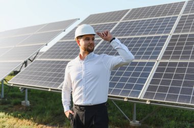 Güneş panellerini incelerken poz veren mühendis. Temiz enerji, sürdürülebilirlik ve yeşil teknoloji gelişimi vurgulanıyor