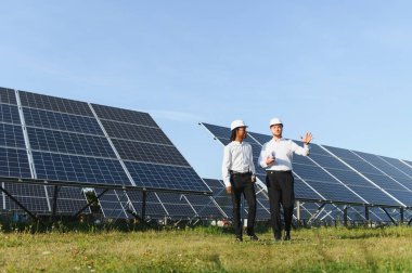 İki farklı mühendis, yenilenebilir enerji çözümleri ve sürdürülebilir enerji üretimini vurgulayarak bir güneş çiftliğinde operasyonları tartışıyor.