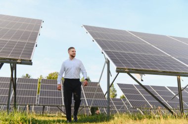 Yenilenebilir enerji, sürdürülebilirlik ve yeşil teknoloji gelişimini temsil eden bir güneş çiftliğini denetleyen işadamı veya mühendis