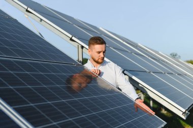Mühendis güneş panellerini kontrol ediyor, yenilenebilir enerji sistemi fonksiyonlarını sağlıyor. Çevresel sürdürülebilirlik için yeşil teknoloji