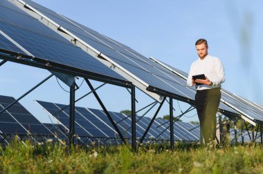 Enerji yönetimi ve sürdürülebilir enerji kullanımı için dijital tablet kullanan güneş paneli performansını gözlemleyen mühendis