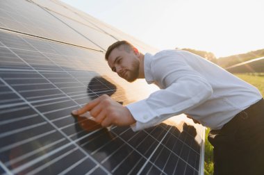 Büyük bir güneş panelini inceleyen adam, sürdürülebilir alternatif enerji üretimi için optimal performans sağlıyor