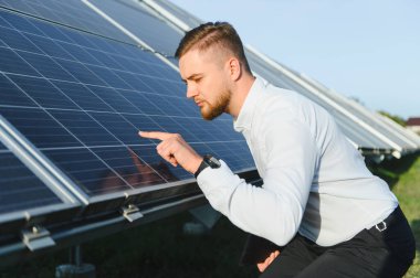 Güneş paneli dizisini inceleyen mühendis, yenilenebilir enerji üretimi ve sürdürülebilir teknoloji geliştirme üzerine odaklanıyor