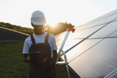 Genç adam güneş panelleri kuruyor, yenilenebilir enerji üretimine ve sürdürülebilir teknoloji gelişimine katkıda bulunuyor