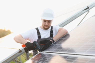 Erkek teknisyen fotovoltaik paneli monte ederek açık havada temiz ve yenilenebilir elektrik üretiyor.