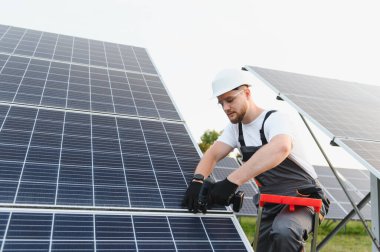 İşçi, sürdürülebilir yeşil enerji ve yenilenebilir enerji üretimine katkıda bulunan bir sondaj ile bir güneş paneli kuruyor