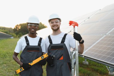 Çeşitli güneş enerjisi teknisyenleri bir güneş enerjisi santralinde birlikte çalışarak temiz ve sürdürülebilir enerjiyi destekliyor.