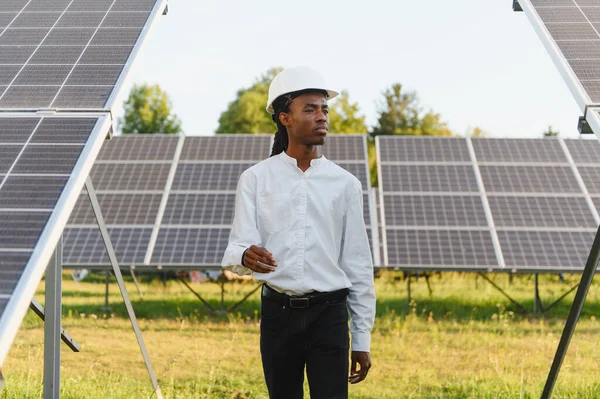 Genç adam güneş paneli dizilerini izliyor, sürdürülebilir bir gelecek için yenilenebilir enerji çözümleri üzerinde çalışıyor