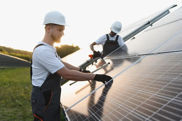 Bir güneş enerjisi santralinde fotovoltaik modüller oluşturan işçiler, yenilenebilir ve temiz enerji çözümleri sunuyorlar