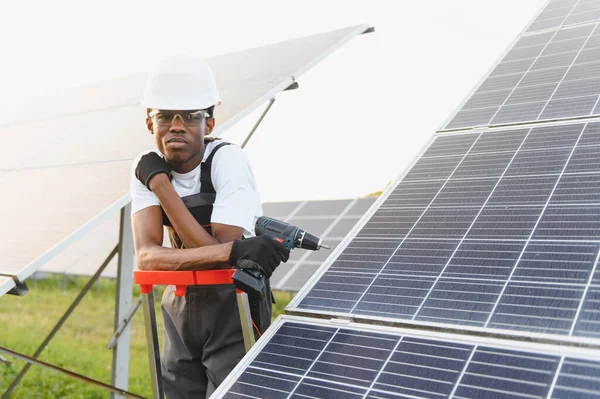 Genç adam yenilenebilir enerji istasyonuna güneş panelleri kuruyor. Sürdürülebilir bir gelecek için çalışmak
