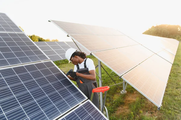 Erkek teknisyen güneş paneli kuruyor. Ticari bir güneş çiftliğinde çalışıyor. Temiz ve sürdürülebilir elektrik üretiyor.