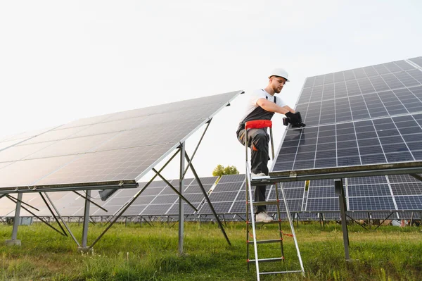 Bir güneş paneli dizisi üzerinde çalışan teknisyen, sürdürülebilir elektrik üretimi için yenilenebilir enerji sistemi kuruyor