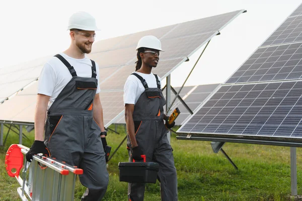 Açık havada çalışan yeşil enerji mühendisleri güneş panelleri kuruyor, yenilenebilir enerji geliştirme ve sürdürülebilirliğe katkıda bulunuyor