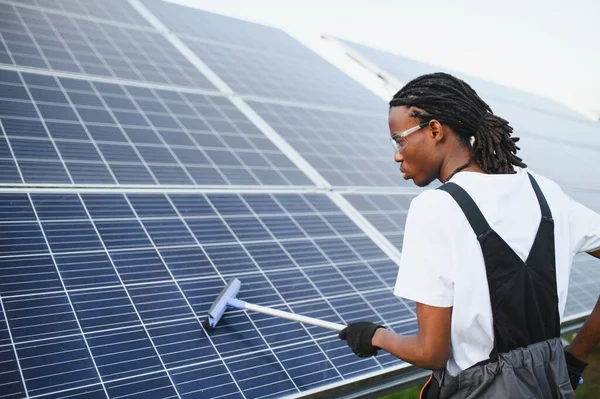 Teknisyen cam sileceği ile güneş paneli yüzeyini temizliyor, elektrik üretimi için optimal verimliliği sağlıyor