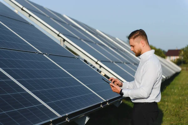 Modern mühendis büyük bir fotovoltaik güneş enerjisi santralinin performansını ve bakımını izlemek için tablet kullanıyor