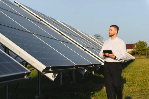Adam, sürdürülebilir enerji üretimi ve yeşil teknoloji çözümleri sağlayan bir tabletle güneş paneli kurulumunu izliyor