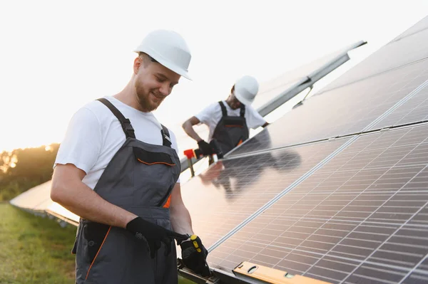 İki teknisyen bir alana güneş panelleri kuruyor, yenilenebilir enerji ve sürdürülebilir elektrik üretimine katkıda bulunuyor