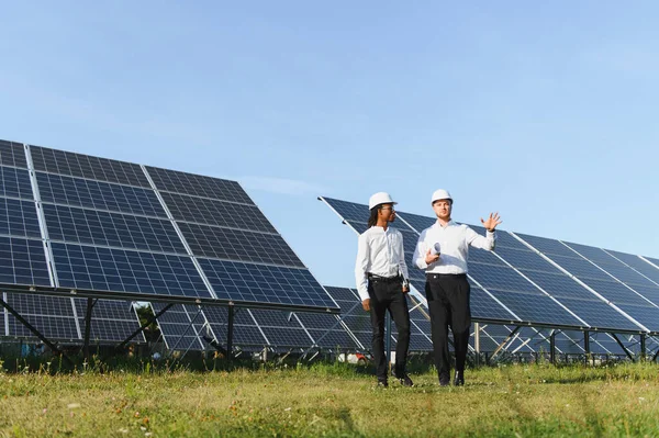 İki farklı mühendis, yenilenebilir enerji çözümleri ve sürdürülebilir enerji üretimini vurgulayarak bir güneş çiftliğinde operasyonları tartışıyor.