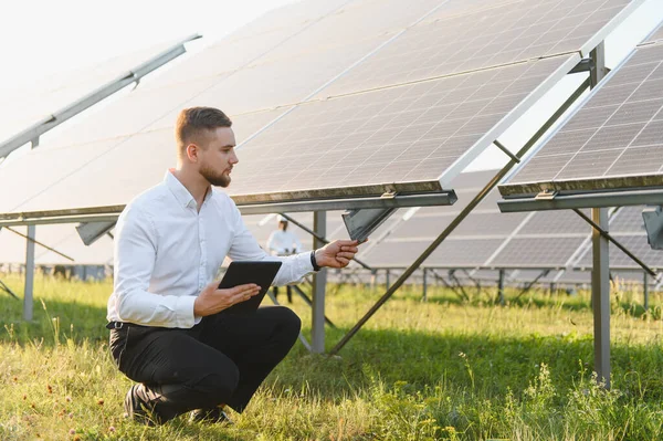 Enerji çiftliğindeki güneş panellerini kontrol eden mühendis veri analizi ve yenilenebilir enerji yönetimi için bir tablet tutuyor.